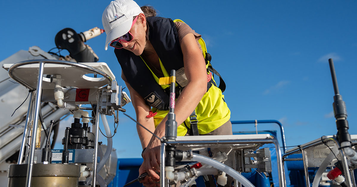 While on the aft deck of Falkor (too), Hilary Close (Scientist, Ocean Sciences at the Rosenstiel School of Marine, Atmospheric, and Earth Science at the University of Miami) examines a sensor, searching for chemical traces that help explain the transformation and transportation of carbon and nitrogen through different depths of the ocean.