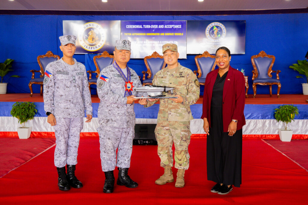 US Embassy Senior Defense Official and Chief of the Joint US Military Assistance Group-Philippines Colonel Daniel Oh (second from right) presents Philippine Fleet Commander Rear Admiral Joe Anthony Cabahug-Orbe (second from left) with a scale model of the Ocean Aero Triton autonomous underwater and surface vehicle during the turnover ceremony at the Philippine Navy’s Naval Operating Base Subic on June 22. They are joined by US Embassy Chargé d’Affaires, a.i., Bridgette Walker (rightmost) and Philippine Navy Unmanned Surface Vessel Unit Acting Commander Lt. Cmdr. Aldwin Pasicolan (leftmost).