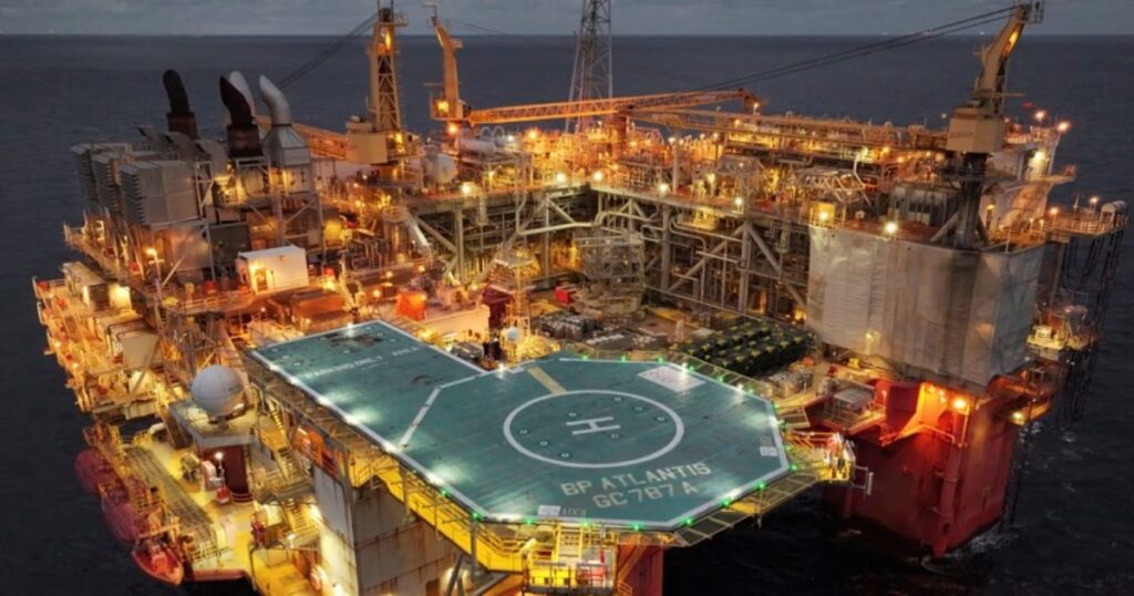 Offshore oil and gas platform illuminated at sea during dusk.