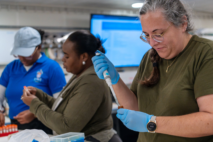 (R-L) Dr. Megan Conkling, Aleisha Dennie, and Cyran Benjamin, work in the Main Lab on RV Falkor (too). Dr. Conkling's work focuses on preserving marine invertebrate biodiversity through cryopreservation. By developing methods to store living tissues long-term, her work could support future restoration efforts and safeguard vulnerable species against ongoing environmental change. (Image credit: Mónika Naranjo González, Schmidt Ocean Institute)