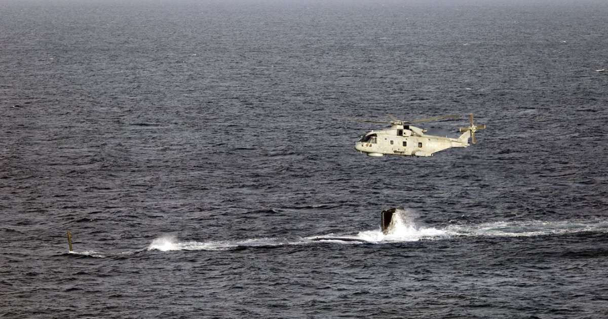 A Merlin Mk2 passes over HMS Agamemnon as the new Astute-class submarine conducts her maiden dive. (Credit: Royal Navy)